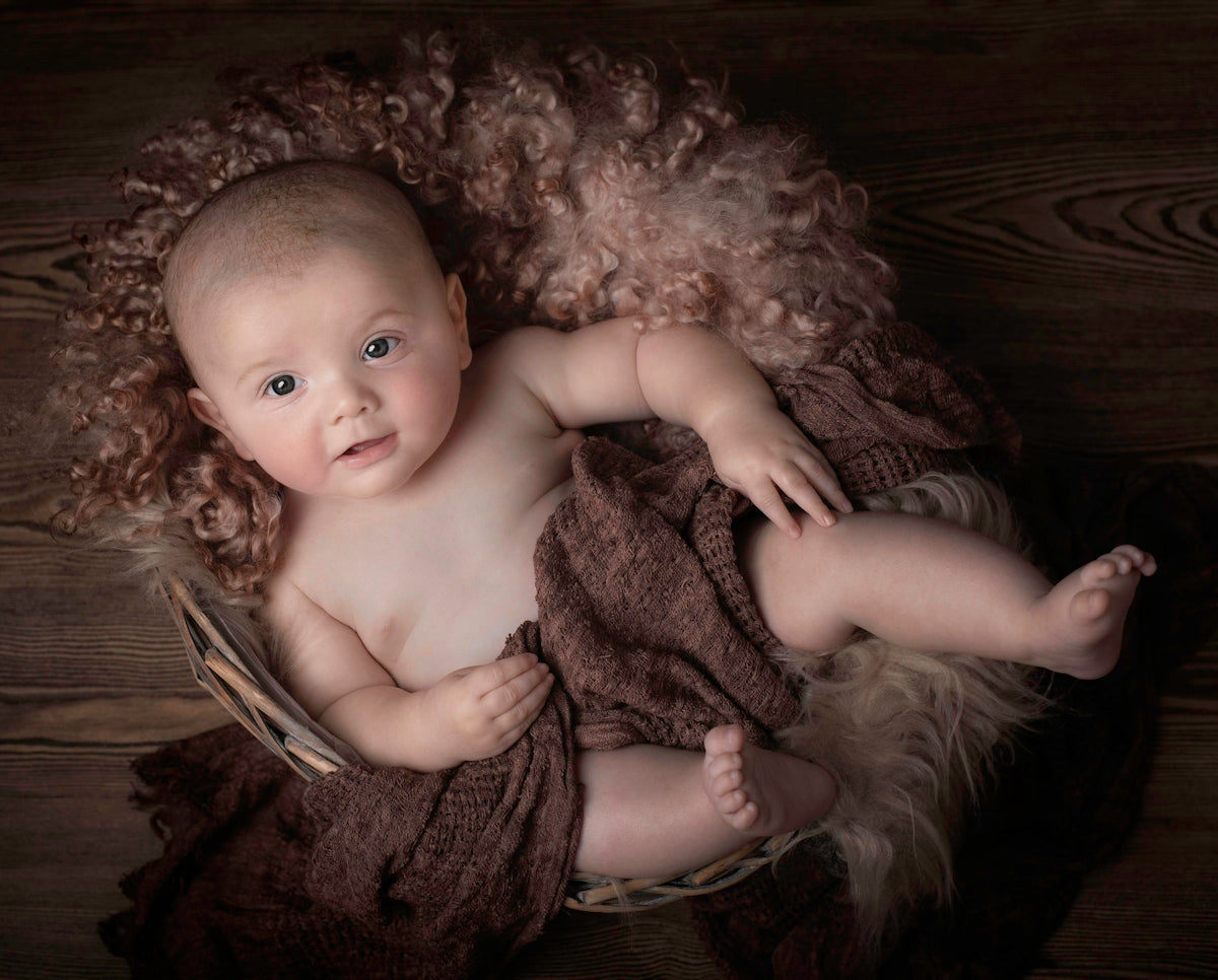 baby lying on brown textile