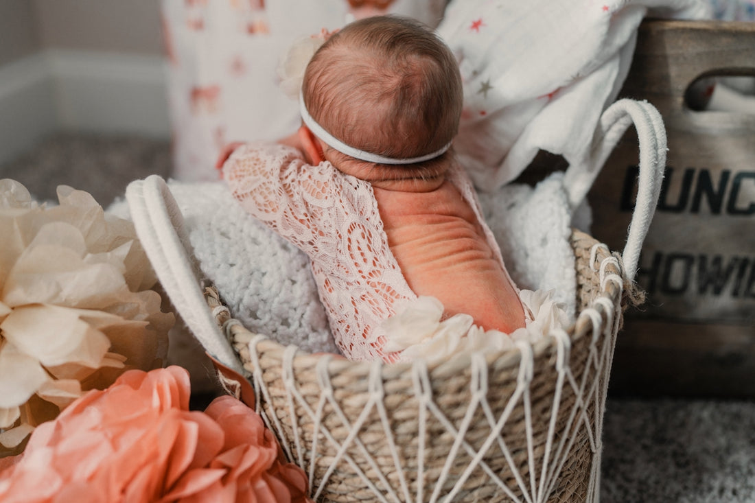 Newborn baby girl in a woven basket with flowers