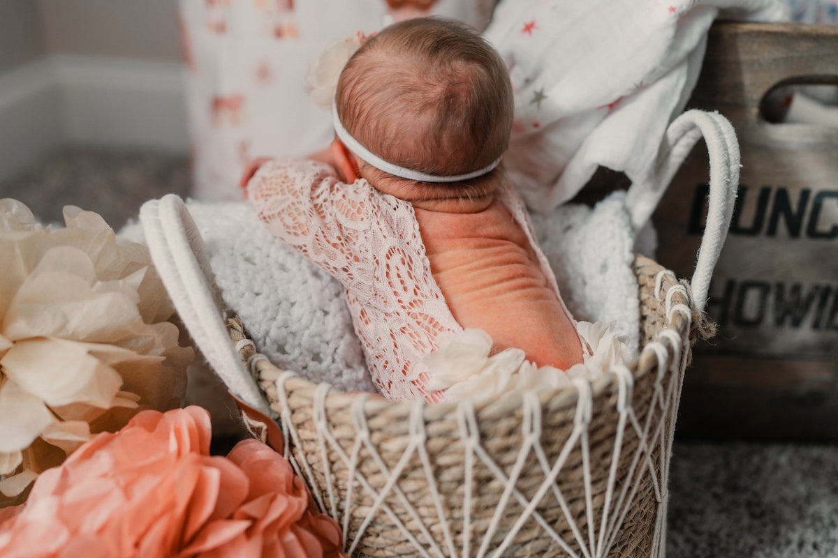 Newborn baby girl in a woven basket with flowers