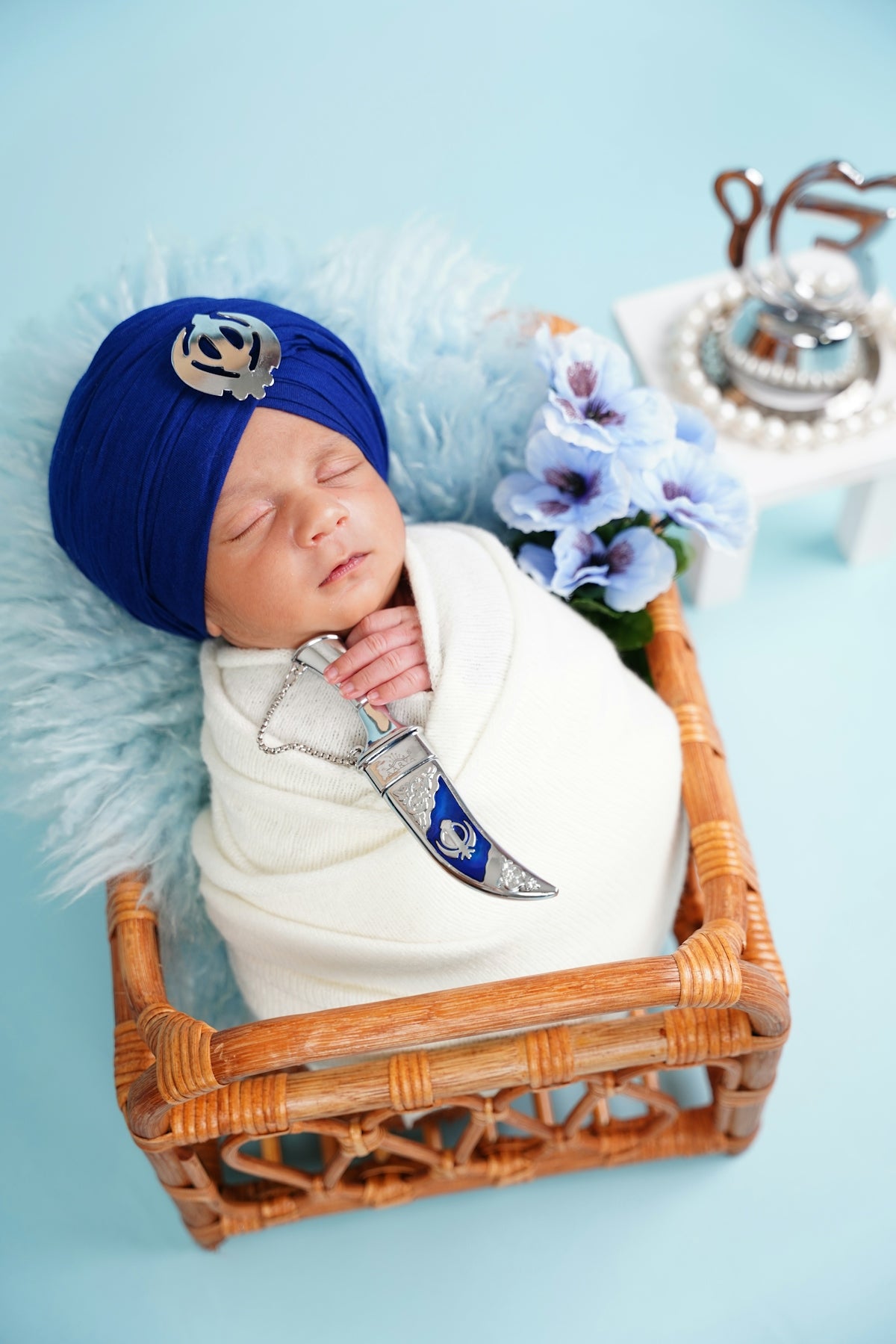 Newborn baby in a blue turban with a ceremonial dagger.