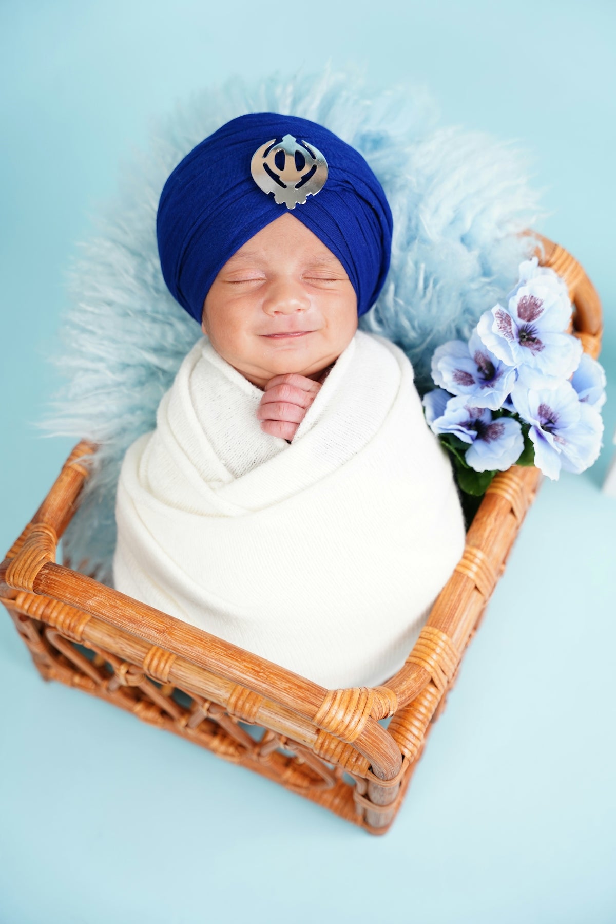 Newborn baby in a blue turban rests in a basket