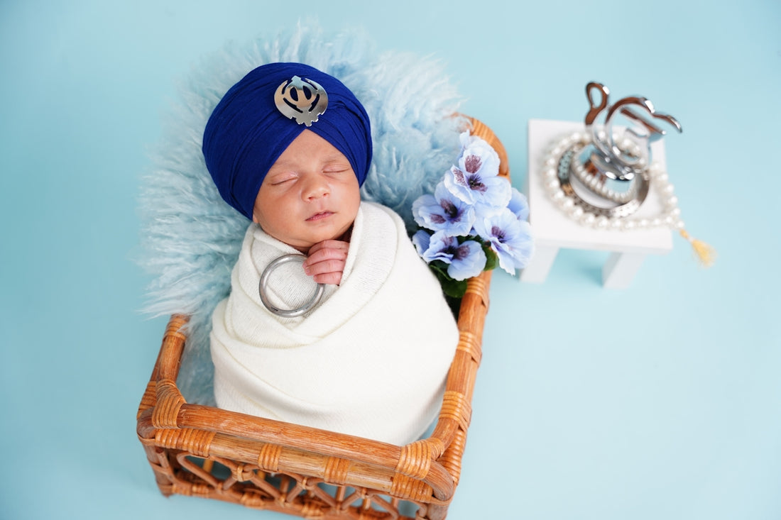 Newborn baby boy in a blue turban and white swaddle.