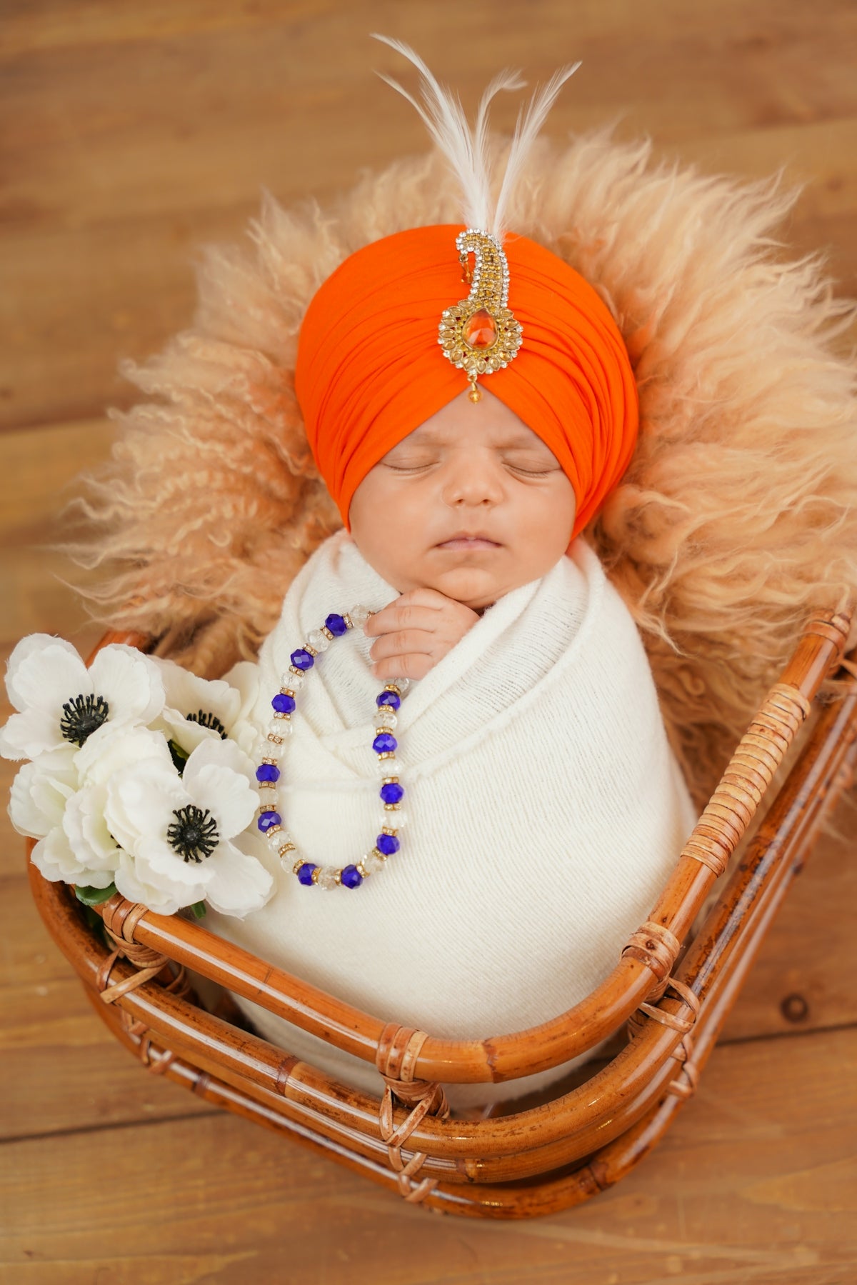 Newborn baby in orange turban sleeps in basket